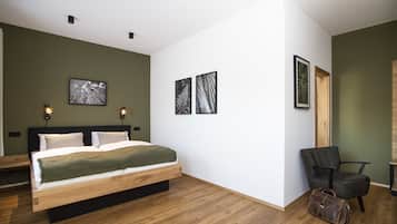 Un dormitorio moderno con cama de madera, paredes verdes y tres cuadros enmarcados.
