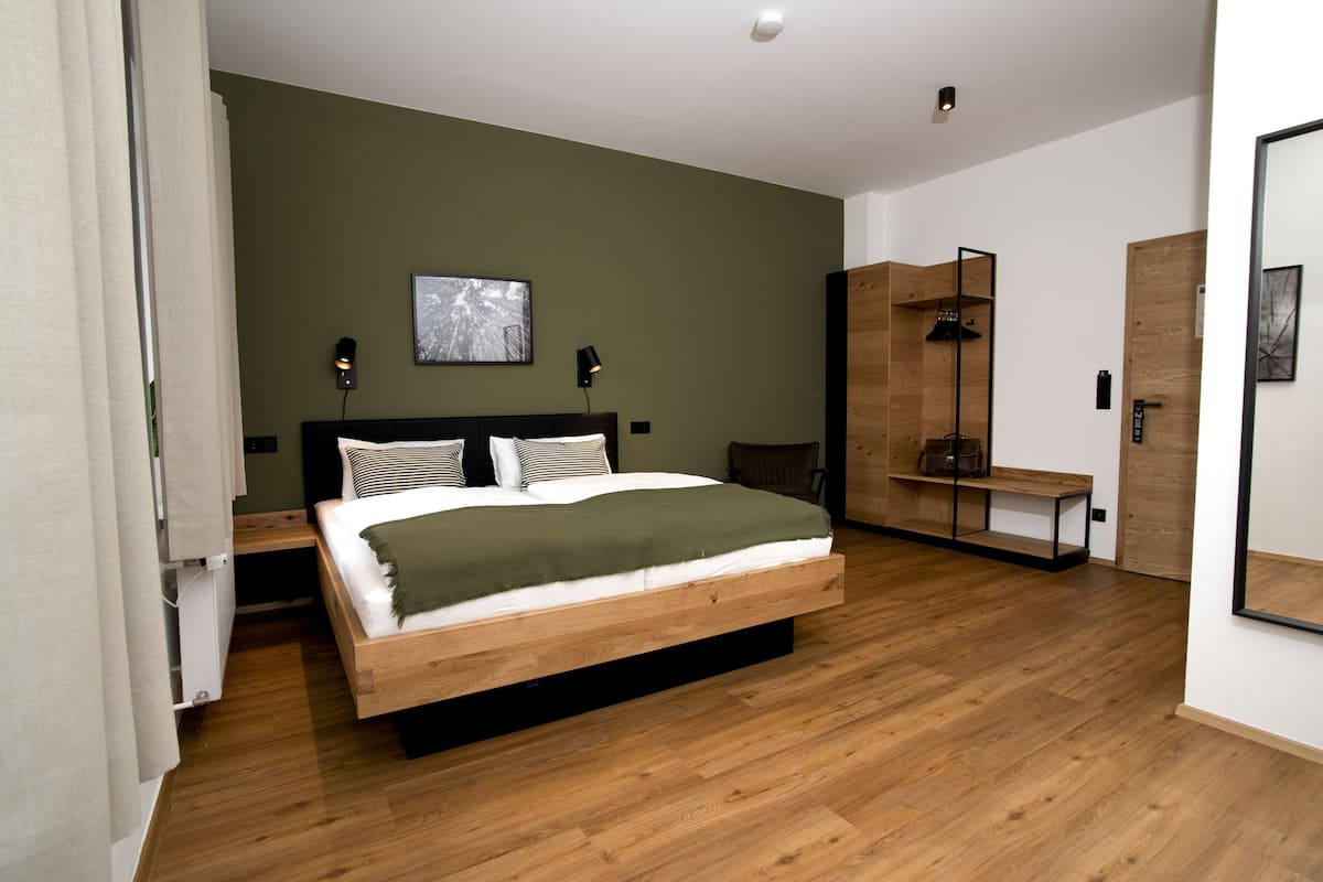 Une chambre à coucher moderne avec un lit en bois, un banc, une armoire et un miroir.