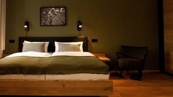 Un dormitorio con cama de madera, dos lámparas de noche, una silla y un cuadro en la pared.