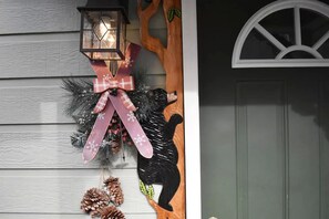 A house entrance with a decorative wreath, a lantern, and a carved tree figure.