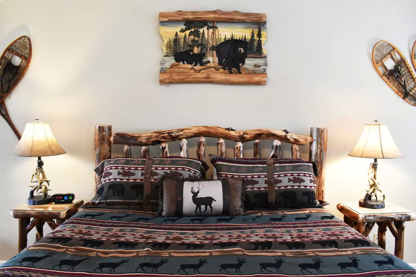 A bed with a wooden headboard, multiple pillows with animal prints, and two bedside tables with lamps.