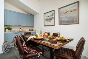 A dining area with a wooden table, brown leather chairs, and a blue kitchen in the background. - Littlefields (Seaton)