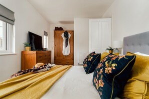 A bedroom with a bed, a wardrobe, a television, and a window. - Littlefields (Seaton)