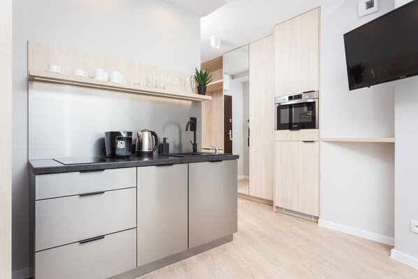 Una cocina moderna con horno empotrado, cafetera y un televisor de pantalla plana montado en la pared.