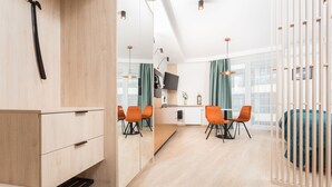 A modern hotel room with a wooden floor, a bed, a desk with a chair, a TV, and a dining area with chairs and a table. - Serviced Apartments G11 - between Main Market Square and Jewish Quarter by InPoint (Kraków)