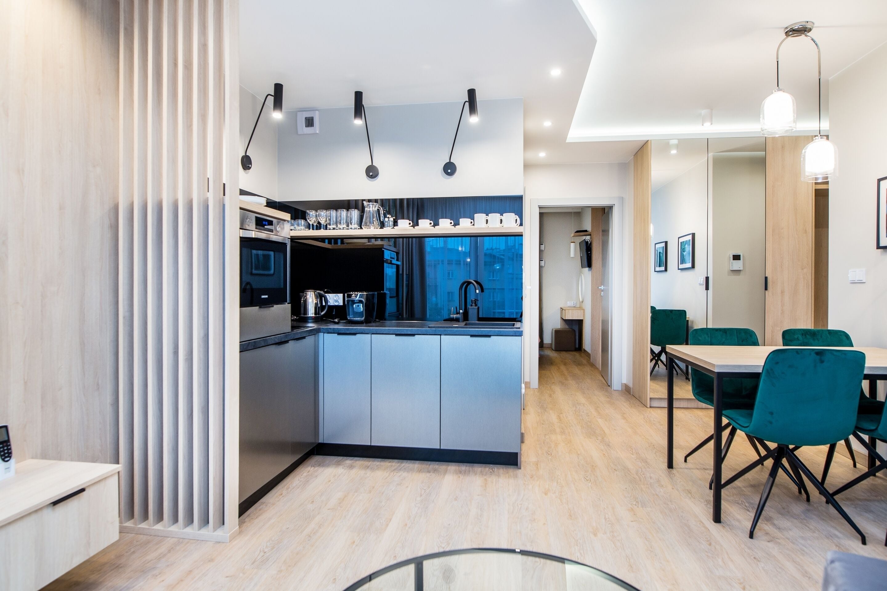 Una cocina moderna con una isla central, electrodomésticos integrados y un comedor con sillas verdes.