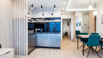 Una cocina moderna con una isla central, electrodomésticos integrados y un comedor con sillas verdes.