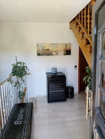 Un pasillo con una escalera, un refrigerador y un cuadro en la pared.