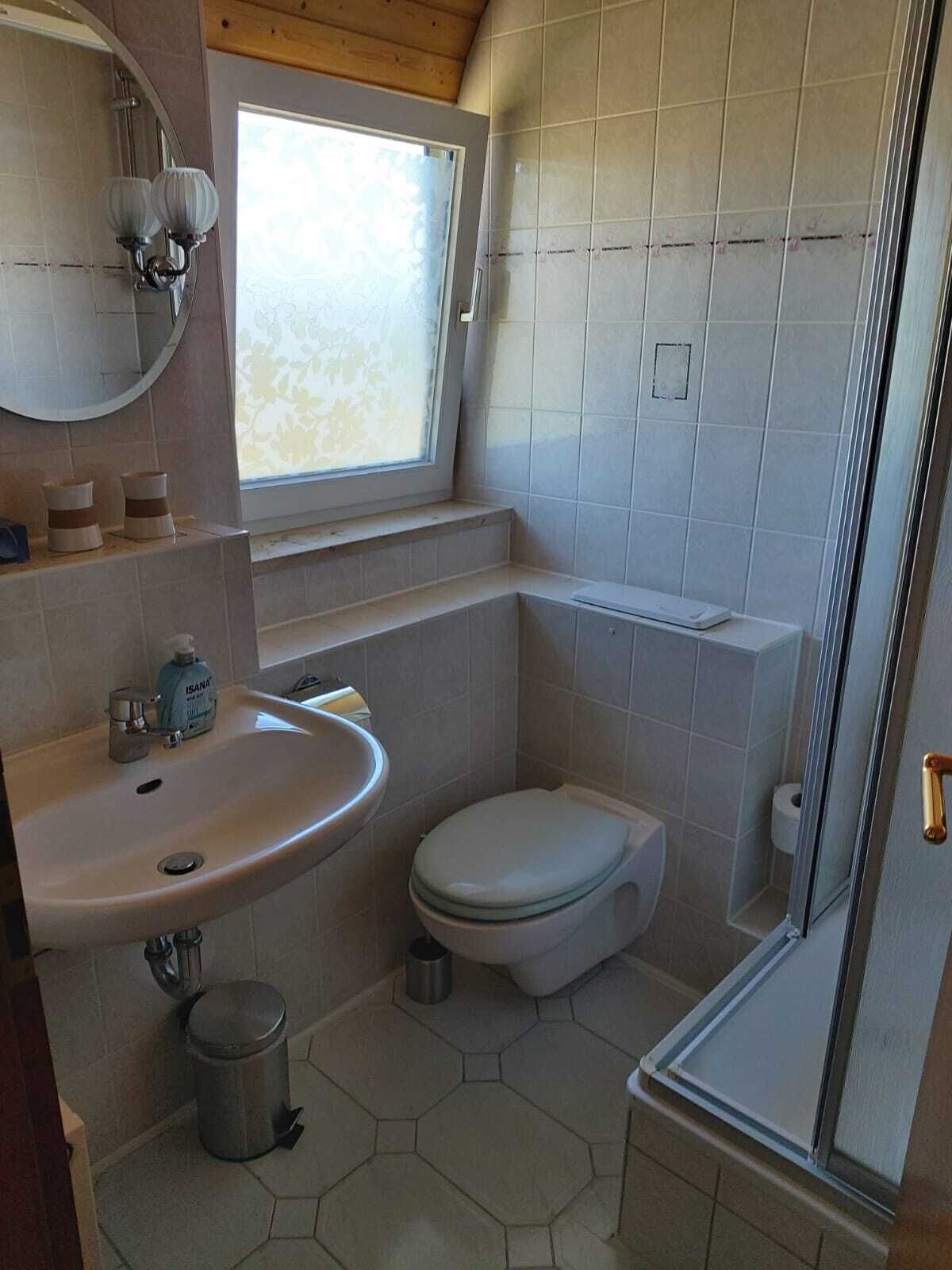 A compact bathroom with a sink, toilet, and shower area.