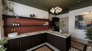 A modern kitchen with dark wood cabinets, a marble countertop, and a pendant light.