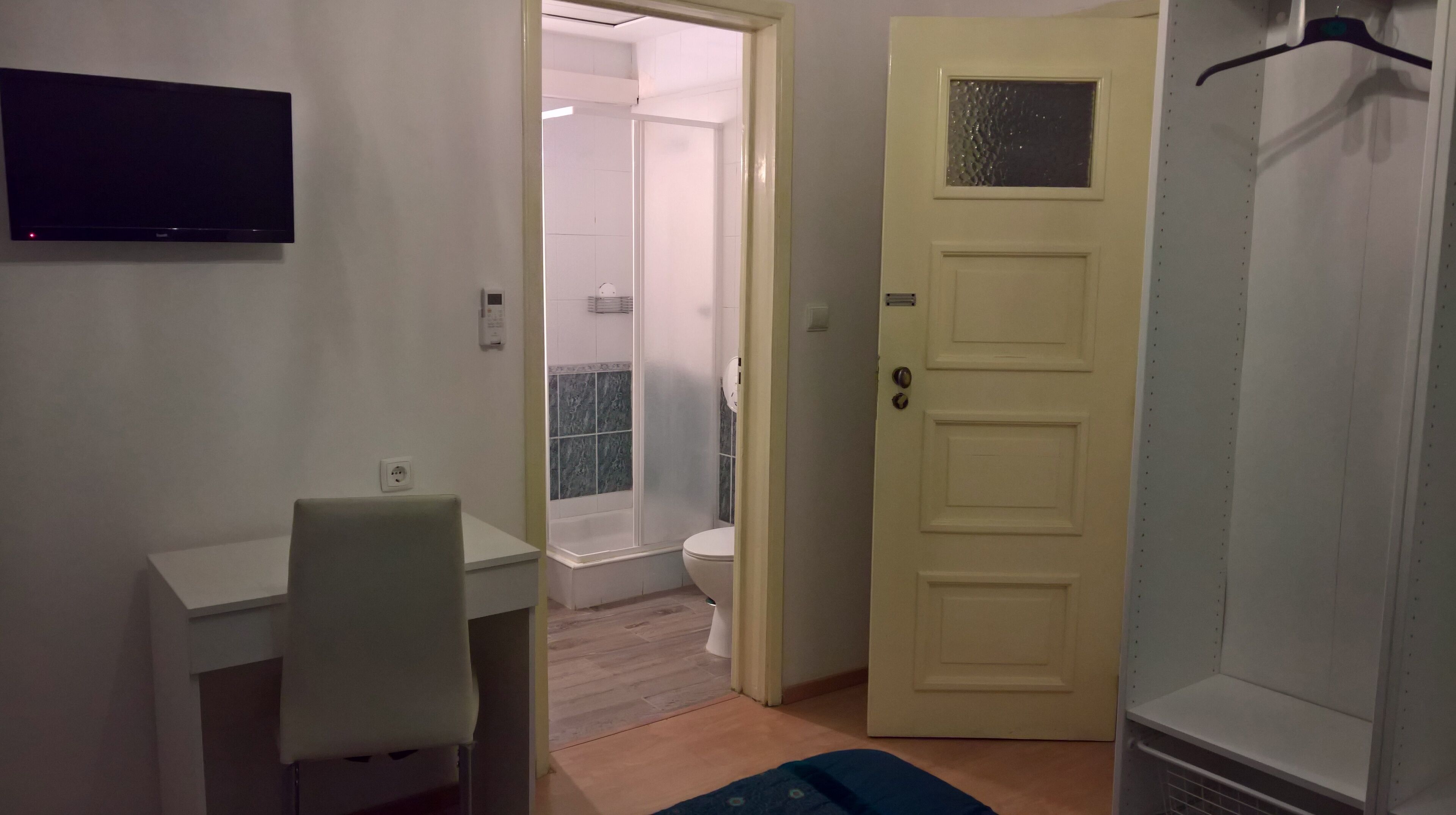 A small room with a desk, chair, and a door leading to a bathroom.