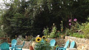 A rustic wooden table with chairs, surrounded by greenery and flowers. - Cottage by the creek, beautiful Mountain View, perfect getaway!!! (Estillfork)