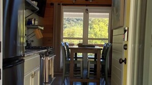 A kitchen with a wooden ceiling, a window, and a dining area with chairs and a table. - Cottage by the creek, beautiful Mountain View, perfect getaway!!! (Estillfork)