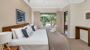 Une chambre d’hôtel avec un lit, un bureau, une fenêtre avec des rideaux et un ventilateur de plafond.