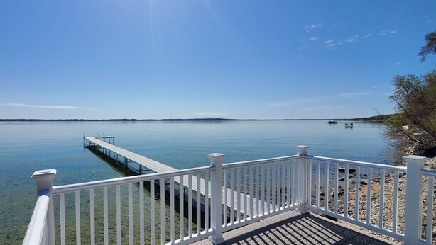 On peut admirer un lac paisible, avec une jetée en bois qui s’avance sur l’eau, le tout étant entouré d’une balustrade blanche.
