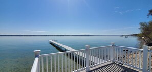 A clear view of a calm lake with a wooden dock extending into the water, surrounded by a white railing.