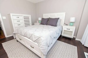 Een slaapkamer met een bed, nachtkastjes, een kast en een kamerbreed tapijt.
