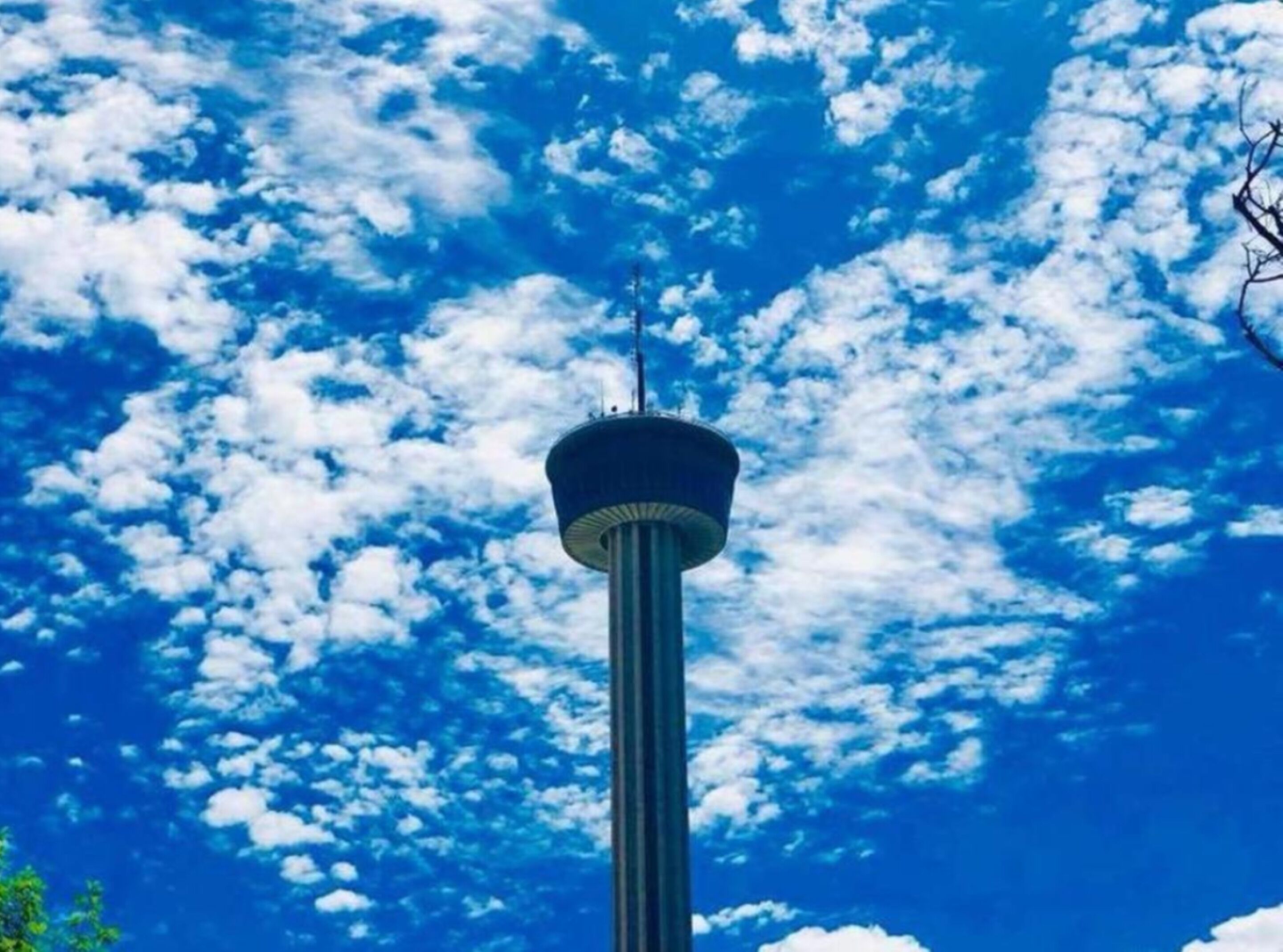 A tower with a circular observation deck against a backdrop of blue sky and scattered clouds.