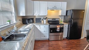 Eine Küche mit weißen Schränken, Edelstahlgeräten, einer Mikrowelle, einem Toaster, einem Backofen und einem Kühlschrank.