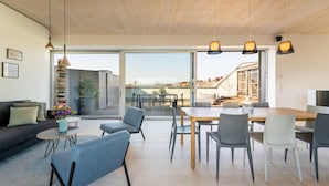 Ein modernes Wohnzimmer mit Sofa, Couchtisch und Essbereich mit Stühlen.
