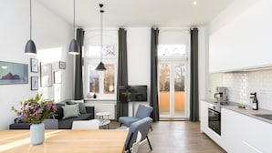 Eine moderne Küche mit Essbereich, einem Fernseher und einem großen Fenster mit Vorhängen.