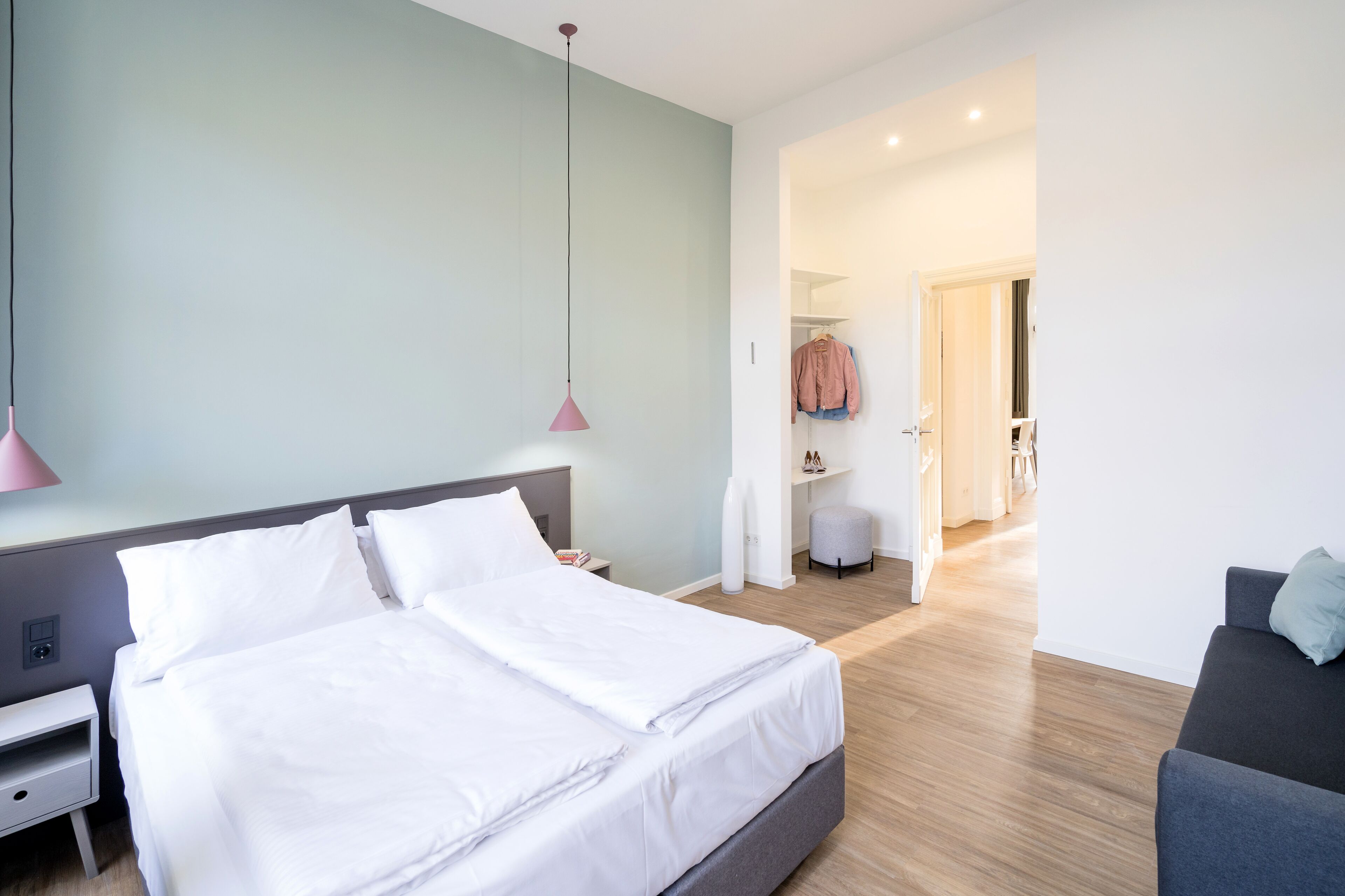 Una habitación de hotel moderna con una cama grande, mesitas de noche, un armario y una zona de estar.