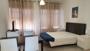 Una camera d'albergo con un letto, una scrivania, una sedia, una lampada e un quadro appeso al muro.