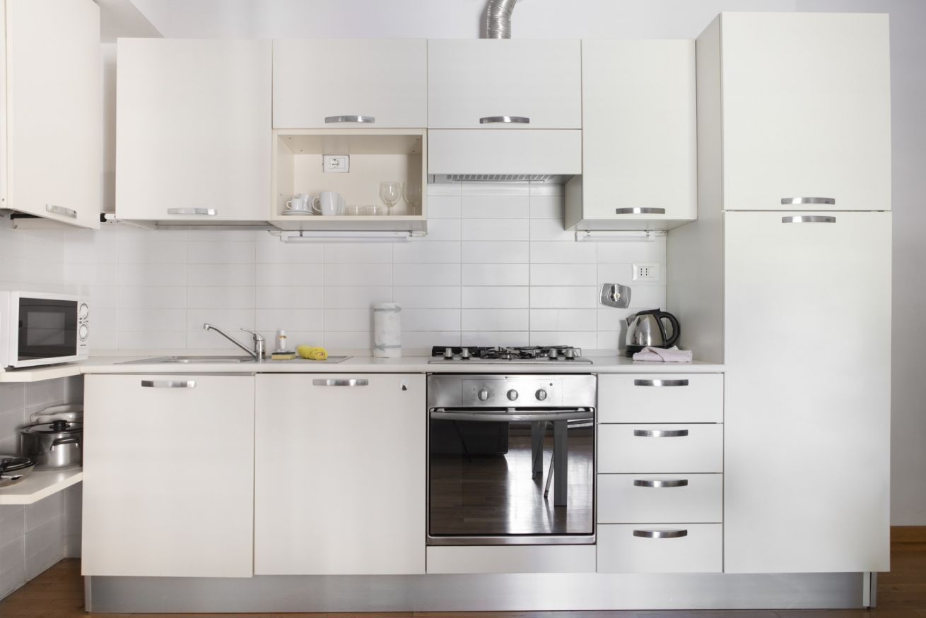 A modern kitchen with white cabinetry, a built-in oven, and a microwave.