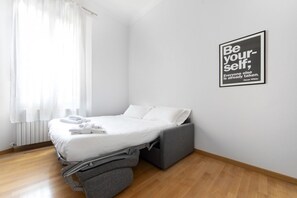 A modern bedroom with a bed, a gray bench, and a motivational quote on the wall.