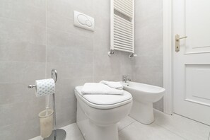 A bathroom with a toilet, bidet, and towel rack.
