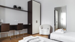 Una habitación de hotel moderna con escritorio, dos sillas, armario, cama y un espejo grande.
