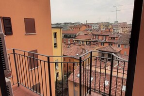 A balcony with a view of a densely packed urban area with terracotta-roofed buildings.