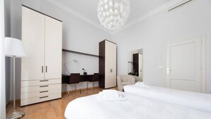 A modern hotel room with two beds, a desk, a wardrobe, and a large mirror.