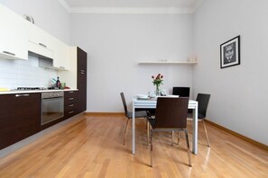 A modern kitchen with dark cabinets, a white countertop, and a dining area with a table and chairs.