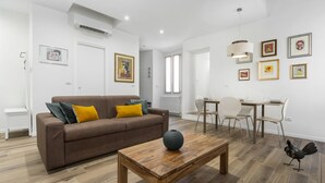 A modern living room with a brown sofa, wooden coffee table, and a dining area with a white table and chairs.