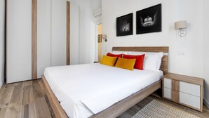 A modern bedroom with a large bed, wooden headboard, and two wall-mounted nightstands.