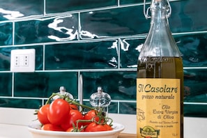 A bottle of Il Casolare extra virgin olive oil with a label, placed on a kitchen counter next to a bowl of tomatoes.