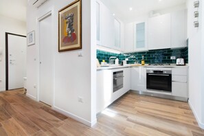 A modern kitchen with white cabinets, a green backsplash, and stainless steel appliances.