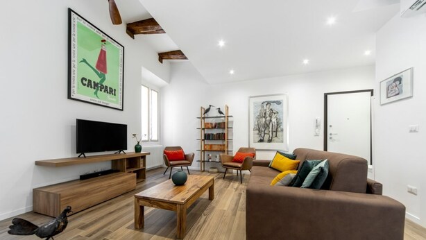 A modern living room with a brown sofa, wooden coffee table, and a bookshelf.