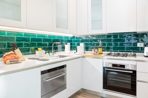 A modern kitchen with white cabinets, a green backsplash, and stainless steel appliances. - UR-NEST Val d'Aposa, Beautiful apartment (Bologna)