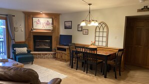Una sala de estar acogedora con chimenea, televisión y comedor con sillas de madera y una mesa.