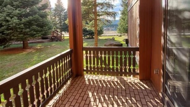 Una terraza de madera con piso de ladrillo y barandilla metálica.