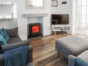A living room with a wood-burning stove, a television, and a sofa.