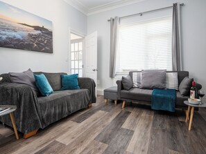 A living room with two grey sofas, a coffee table, and a window with blinds.