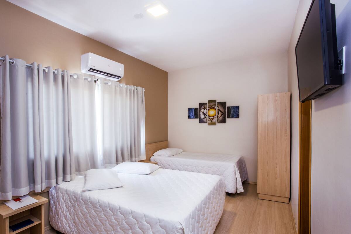 Ett hotellrum med två sängar, en TV, luftkonditionering och en garderob i trä.