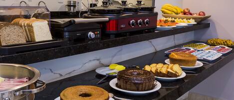 A buffet with various food items including cakes, bread, and fruits.