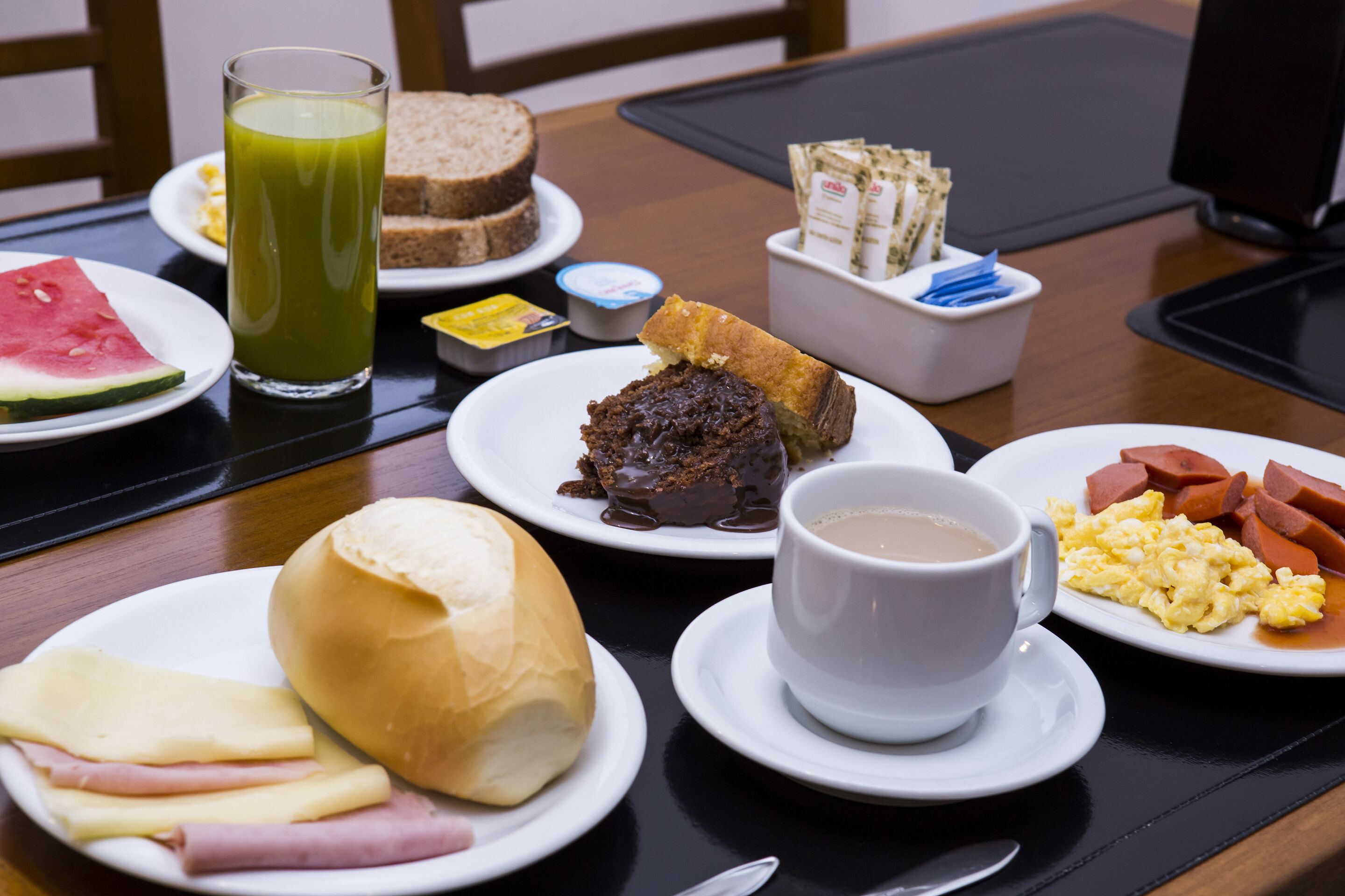 A breakfast table with various food items including toast, eggs, sausage, and a cup of coffee.