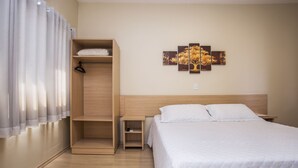 Un dormitorio con una cama, un armario de madera, una mesita de noche y una obra de arte en la pared.