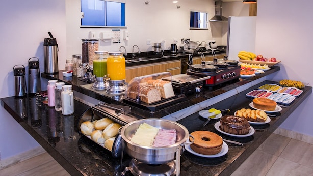 Un bufé con diversos alimentos, entre ellos pan, frutas y un recipiente con comida caliente.