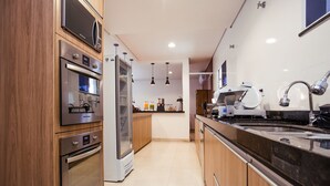 Una cocina moderna con electrodomésticos de acero inoxidable, armarios de madera y una encimera negra.